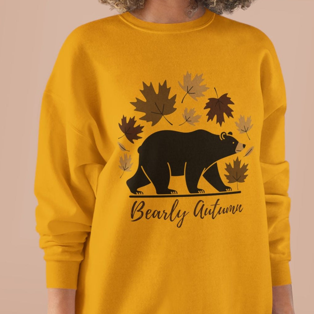 Woman wearing a yellow sweatshirt with a bear and leaf design on a beige background